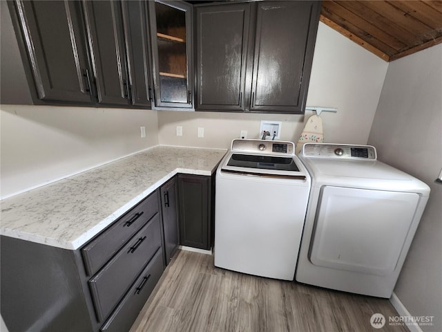 washroom featuring cabinet space, washing machine and dryer, and light wood-style floors