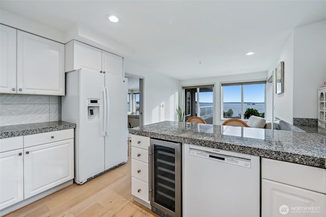 kitchen featuring wine cooler, white appliances, light wood-type flooring, white cabinetry, and recessed lighting