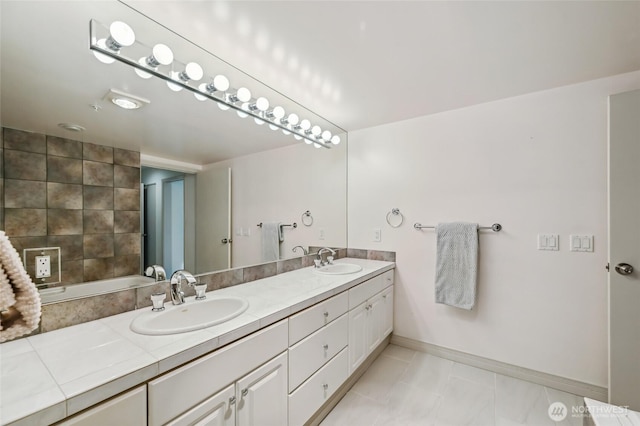 bathroom with double vanity, baseboards, and tile patterned flooring