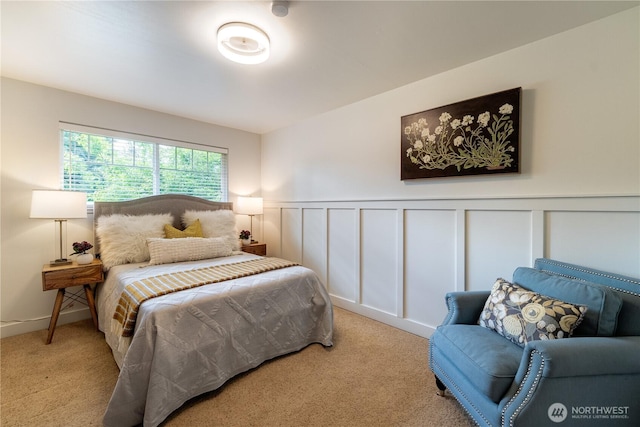 bedroom with a decorative wall, carpet flooring, and wainscoting