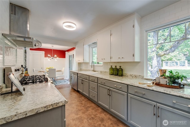 kitchen featuring gray cabinets, island range hood, light countertops, a sink, and a chandelier