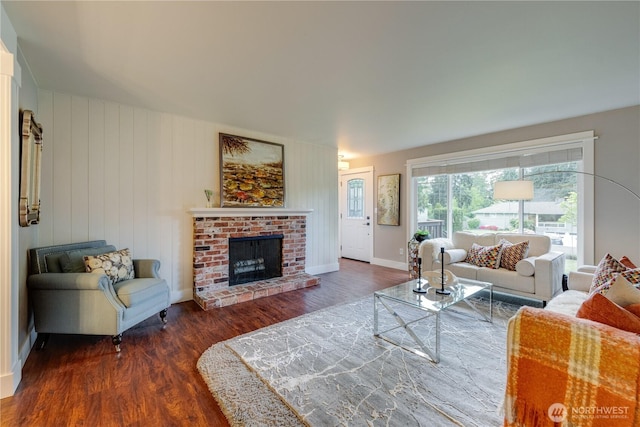 living room featuring wood finished floors, a brick fireplace, and baseboards