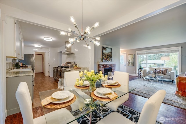 dining area featuring a chandelier, baseboards, and a brick fireplace