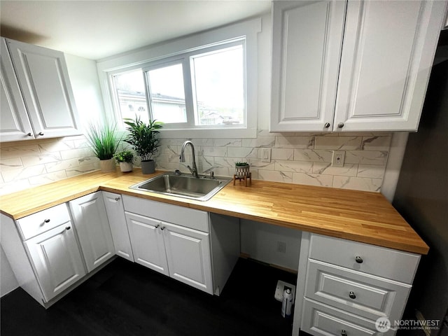 kitchen featuring a sink, wooden counters, and white cabinets