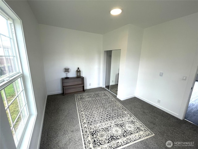unfurnished bedroom with baseboards and dark carpet