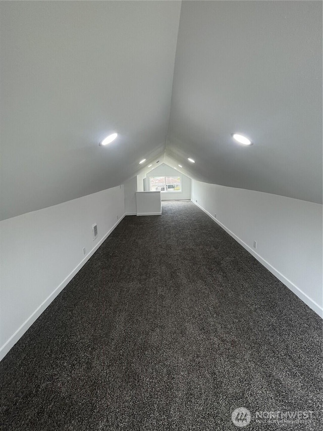 bonus room featuring lofted ceiling, baseboards, and dark colored carpet