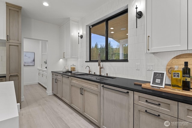 6993 N Fork Rd SE, Snoqualmie, WA 98065 - kitchen with a sink, backsplash, dark countertops, light wood finished floors, and baseboards