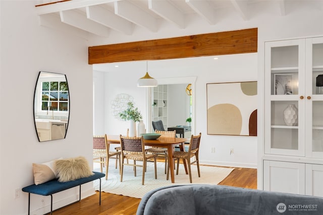 dining area with beam ceiling, wood finished floors, and baseboards