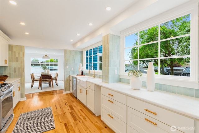 kitchen featuring a sink, appliances with stainless steel finishes, light countertops, white cabinets, and recessed lighting