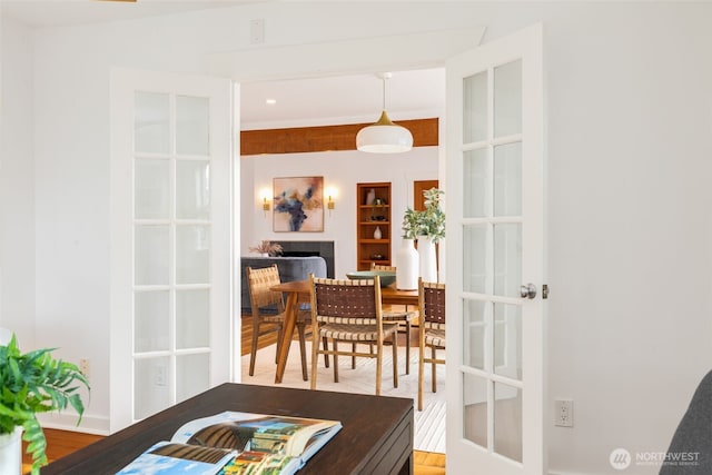 dining room with a tiled fireplace, french doors, and built in shelves