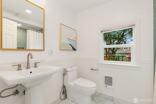 full bath with heating unit, a wainscoted wall, toilet, and curtained shower