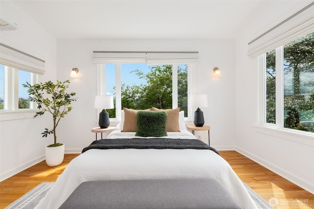 bedroom featuring multiple windows, wood finished floors, and baseboards