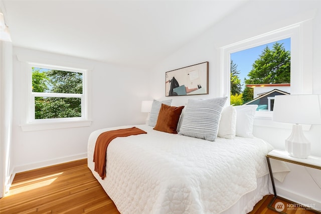 bedroom featuring wood finished floors, baseboards, and vaulted ceiling