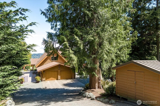 7353 Cedar House Ct, Clinton, WA 98236 - view of front of house with an outbuilding, a garage, driveway, a standing seam roof, and metal roof