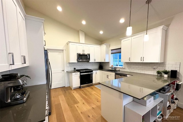 81 E Sullivan St, Allyn, WA 98524 - kitchen with appliances with stainless steel finishes, a sink, dark countertops, a peninsula, and white cabinetry
