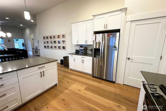 81 E Sullivan St, Allyn, WA 98524 - kitchen featuring stainless steel fridge with ice dispenser, light wood-style floors, dark countertops, decorative backsplash, and lofted ceiling