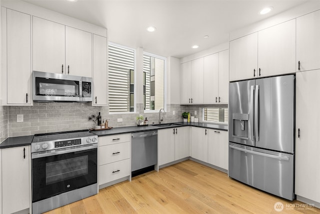 1108B 34th Ave, Seattle, WA 98122 - kitchen with appliances with stainless steel finishes, dark countertops, decorative backsplash, recessed lighting, and light wood finished floors