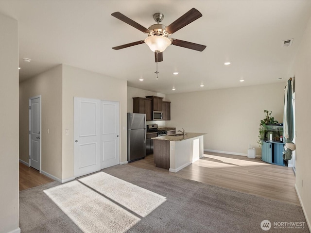 12029 317th Dr SE, Sultan, WA 98294 - kitchen with appliances with stainless steel finishes, a kitchen island with sink, a ceiling fan, light wood-style flooring, and open floor plan