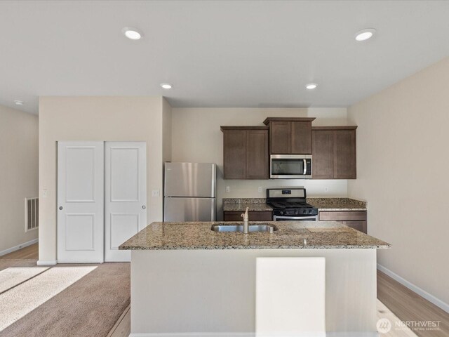 12029 317th Dr SE, Sultan, WA 98294 - kitchen with stainless steel appliances, light stone counters, an island with sink, dark brown cabinets, and recessed lighting