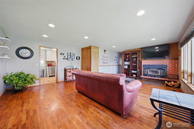 living room with recessed lighting, wood finished floors, a wainscoted wall, and a wood stove