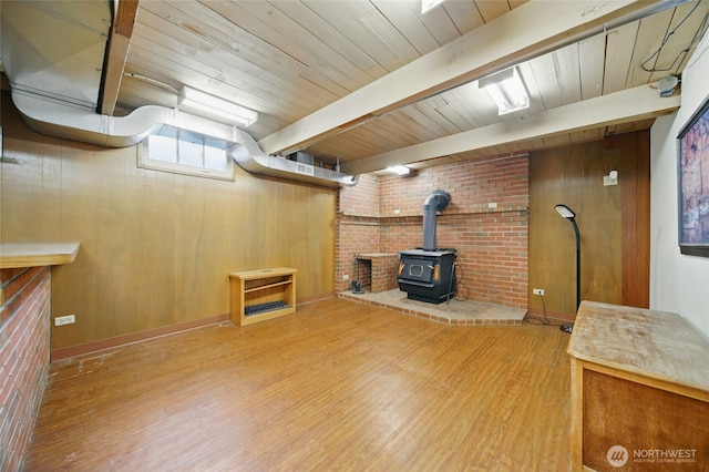 basement featuring a wood stove, wood finished floors, wooden ceiling, and wooden walls