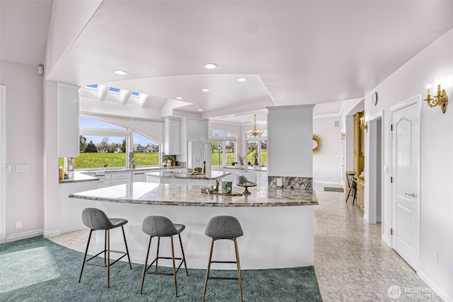 325 Island Green Way, Lynden, WA 98264 - kitchen featuring white cabinetry, a kitchen bar, light stone counters, baseboards, and recessed lighting
