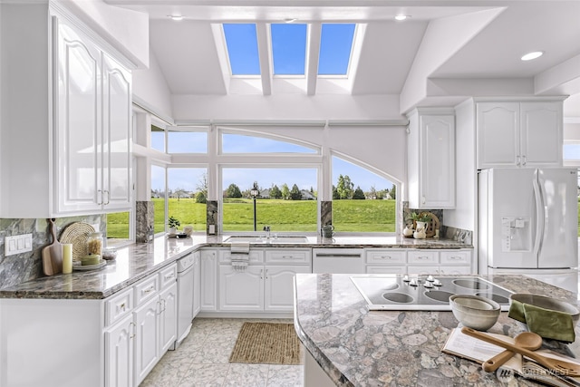 325 Island Green Way, Lynden, WA 98264 - kitchen with lofted ceiling, white appliances, white cabinetry, and dark stone countertops
