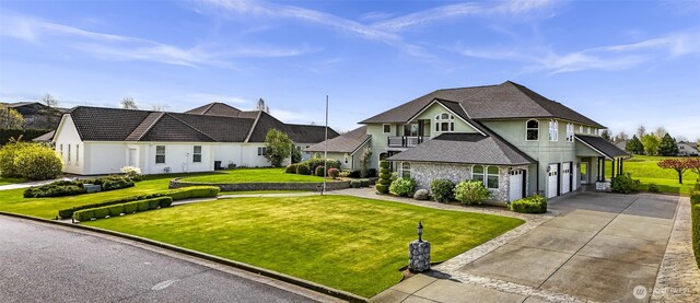 325 Island Green Way, Lynden, WA 98264 - view of front of property with driveway, a front yard, stone siding, an attached garage, and stucco siding