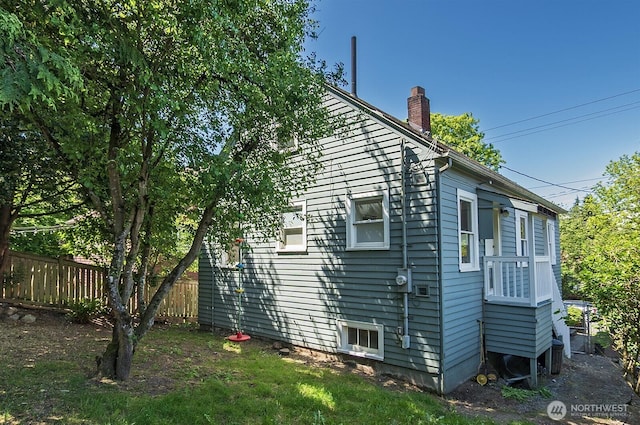 view of side of property with fence and a chimney