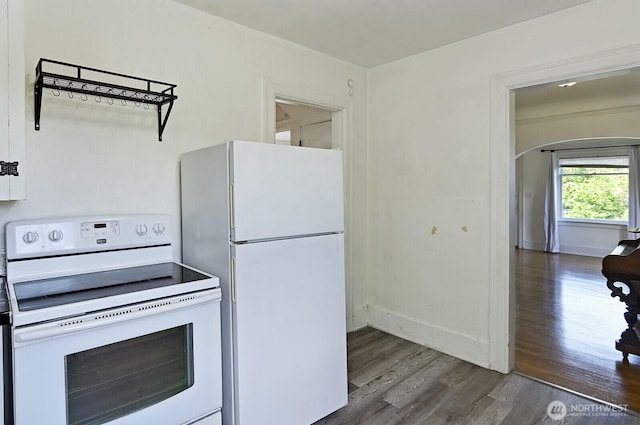 kitchen with white appliances, wood finished floors, arched walkways, and baseboards