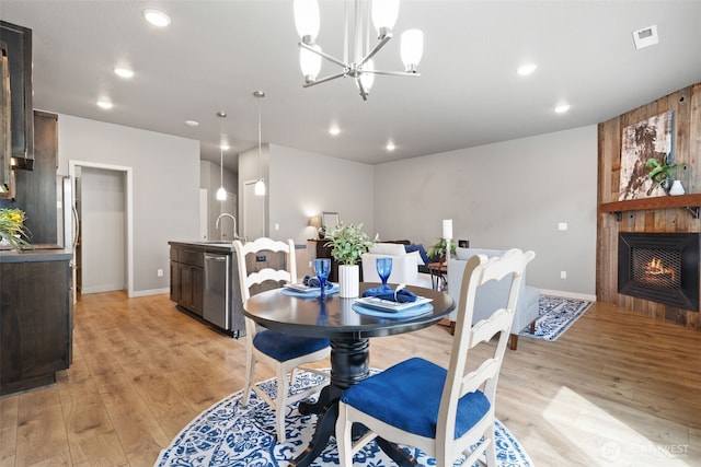 12313 NE 116th St N, Vancouver, WA 98682 - dining space with light wood-style flooring, a large fireplace, baseboards, recessed lighting, and a chandelier