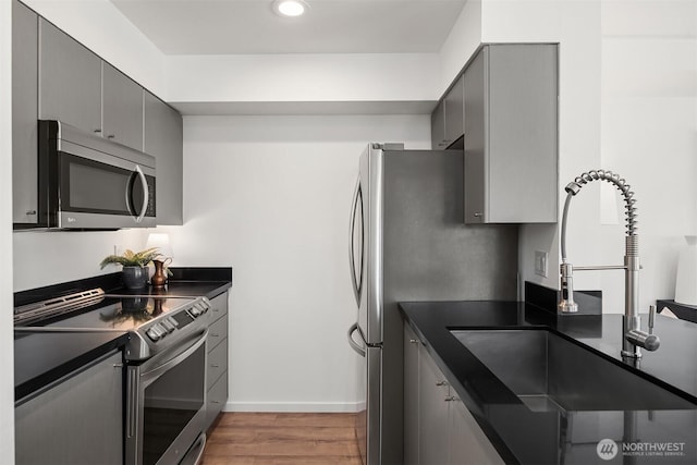 1125 E Olive St Unit 501, Seattle, WA 98122 - kitchen featuring appliances with stainless steel finishes, a sink, gray cabinetry, dark countertops, and recessed lighting