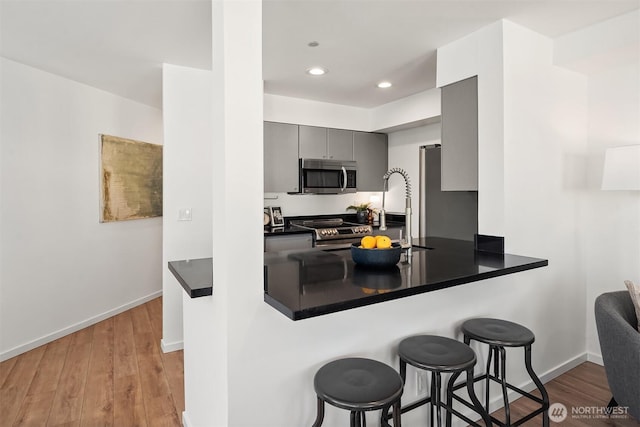 1125 E Olive St Unit 501, Seattle, WA 98122 - kitchen with appliances with stainless steel finishes, gray cabinets, dark countertops, a kitchen breakfast bar, and recessed lighting