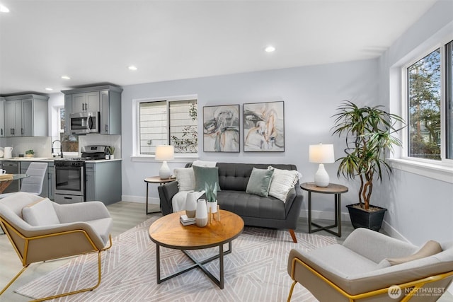 living room featuring healthy amount of natural light, recessed lighting, light wood-style flooring, and baseboards