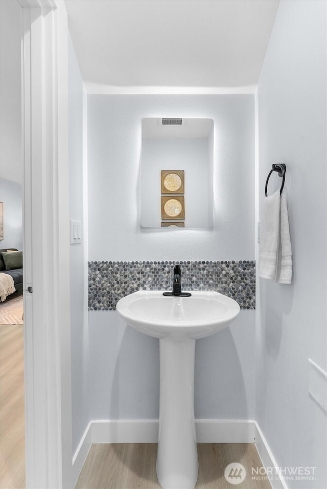 bathroom with wood finished floors, a sink, and baseboards