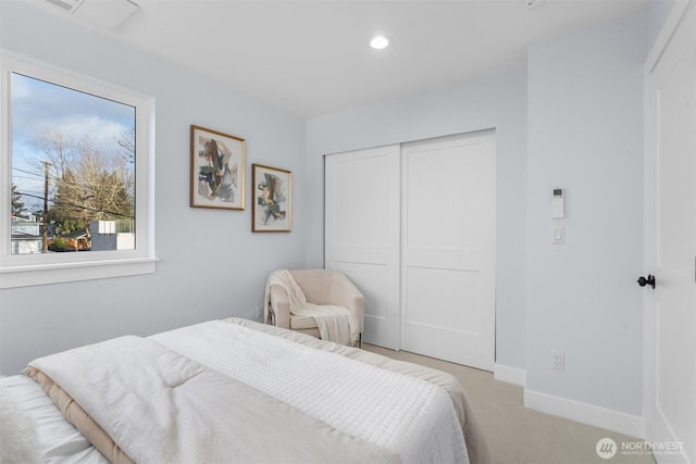 bedroom with a closet, light carpet, recessed lighting, and baseboards