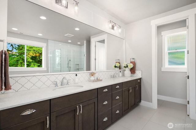 full bathroom with backsplash, a shower stall, double vanity, tile patterned floors, and baseboards