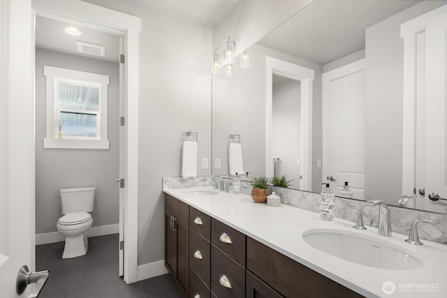 bathroom with tile patterned flooring, double vanity, toilet, and baseboards