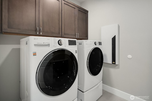 laundry area featuring washer and dryer, cabinet space, baseboards, and light tile patterned floors