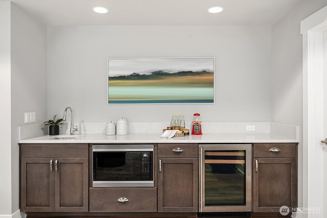bar area with beverage cooler, stainless steel microwave, a sink, and recessed lighting