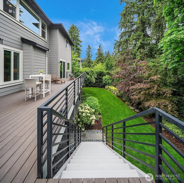 wooden deck featuring outdoor dining area and a yard