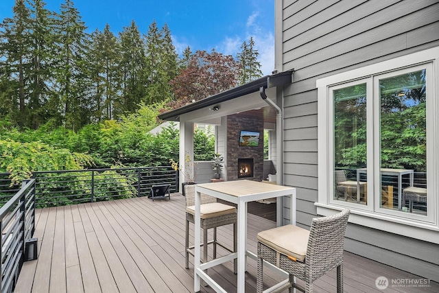 wooden terrace featuring a stone fireplace