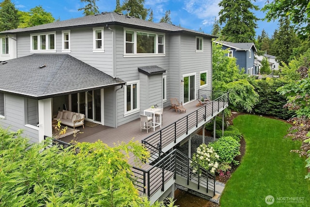 rear view of property with roof with shingles, a deck, a yard, and an outdoor living space