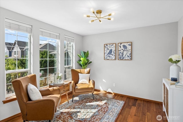 sitting room featuring a chandelier, baseboards, plenty of natural light, and wood finished floors