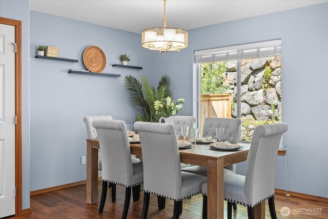 dining room featuring a chandelier, wood finished floors, and baseboards
