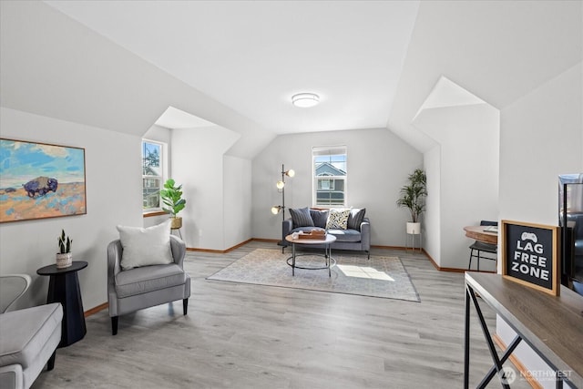 living area featuring vaulted ceiling, light wood-style flooring, and baseboards