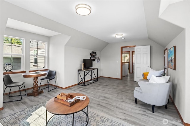 sitting room with light wood-type flooring, baseboards, and lofted ceiling