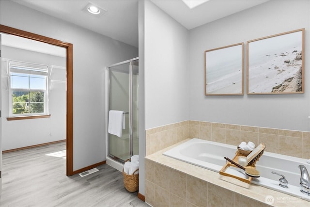 full bathroom with a shower stall, wood finished floors, and a bath