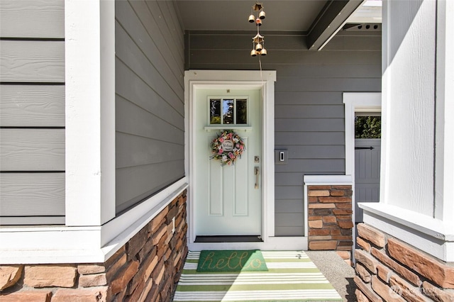 view of exterior entry with stone siding and covered porch