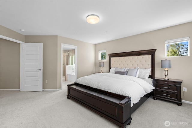 bedroom featuring light colored carpet, baseboards, and connected bathroom